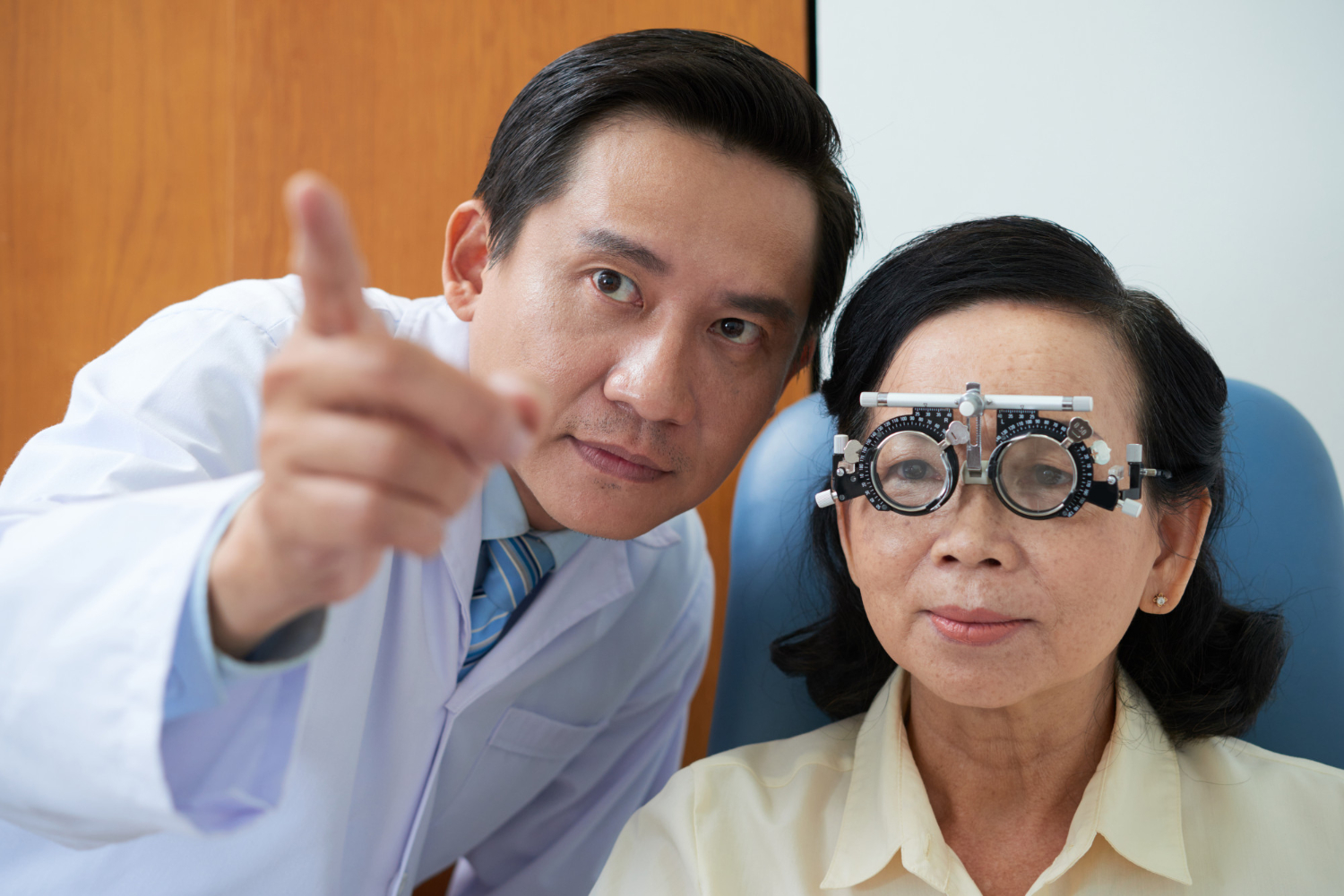 Senior asian lady wearing trial lens frame and ophtalmologist pointing during eyesight checkup